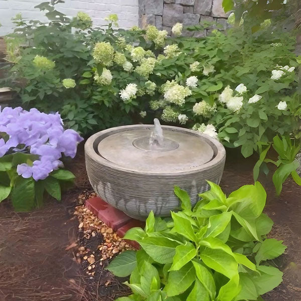 Girona Fountain in action in the backyard against plants