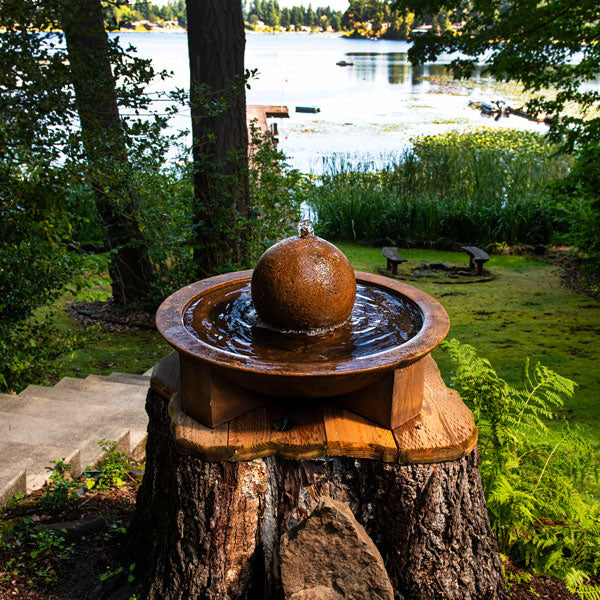 Low Zen Sphere fountain sitting on tree stump in action near lake