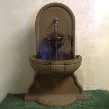 Absolute Wall Fountain on grass against brown background.