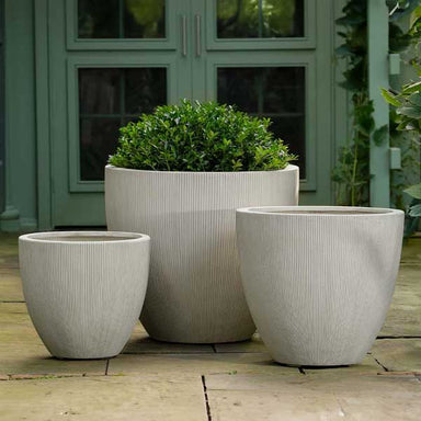 Airy Planter, Medium -Alabaster Lite on concrete filled with plants