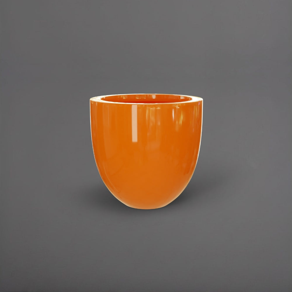 Alzira Round Fiberglass Planter in gloss tangerine against gray background.