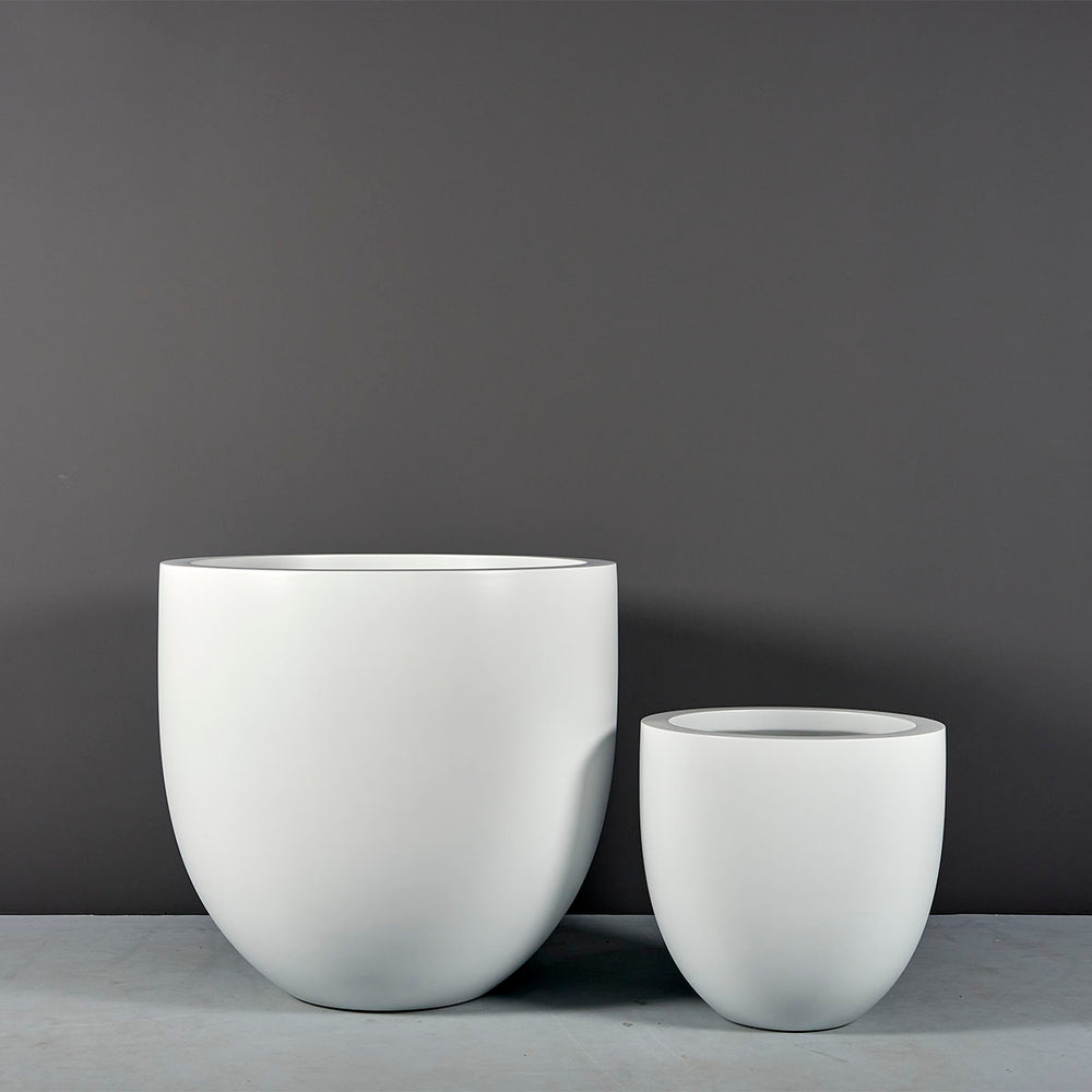 Alzira Round Fiberglass Planter on concrete shown with different sizes.