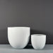 Alzira Round Fiberglass Planter on concrete shown with different sizes.