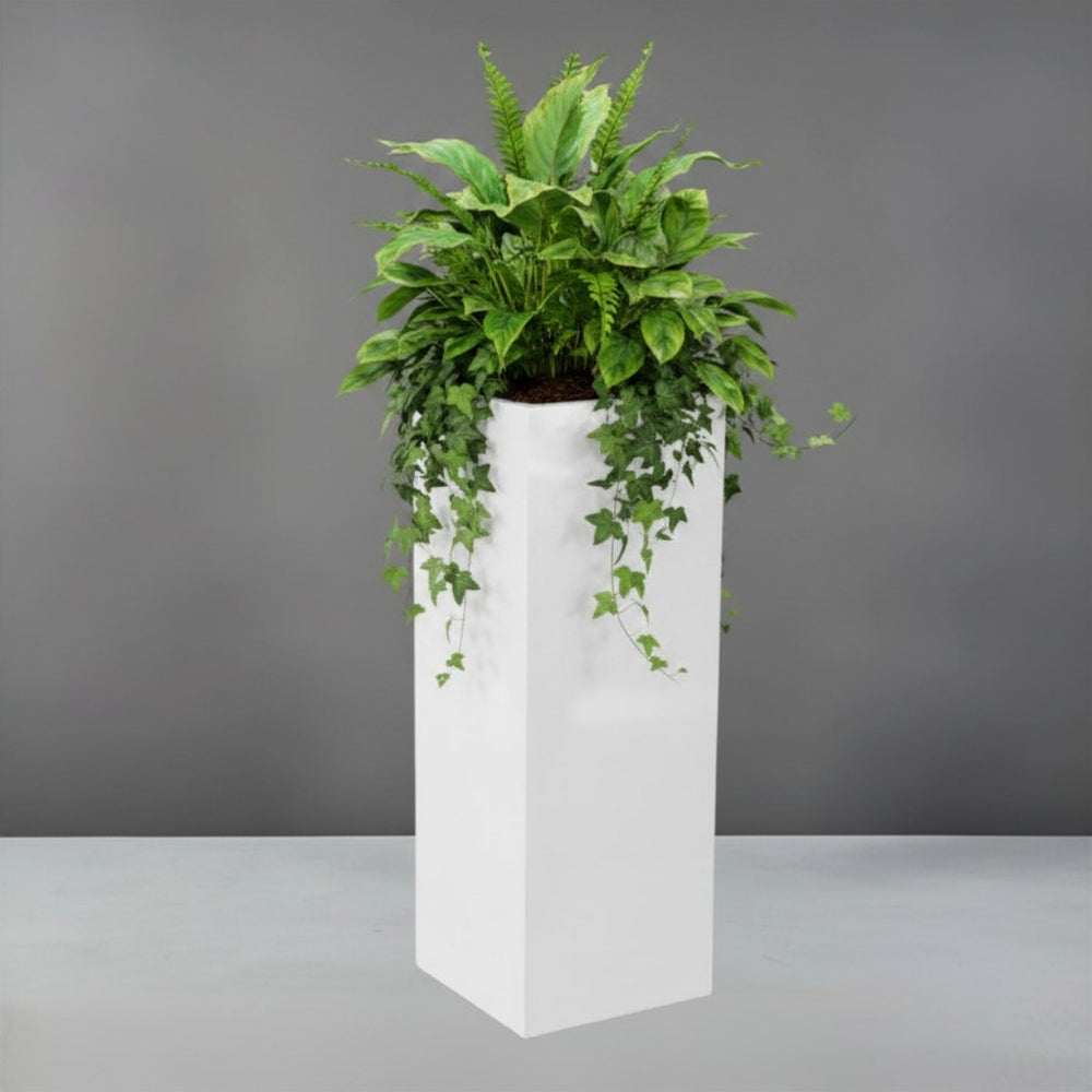 Amesbury Tall Corner Planter filled with plants against gray backdrop