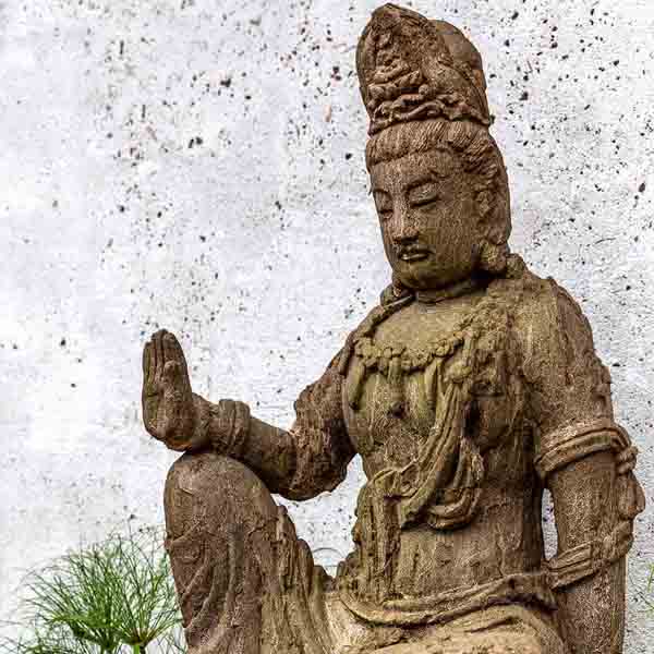 Antique Quan Yin Fountain on gravel in the backyard upclose