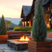 Asheville Cube Wood Look Fiberglass Planter filled with plants beside a fireplace.