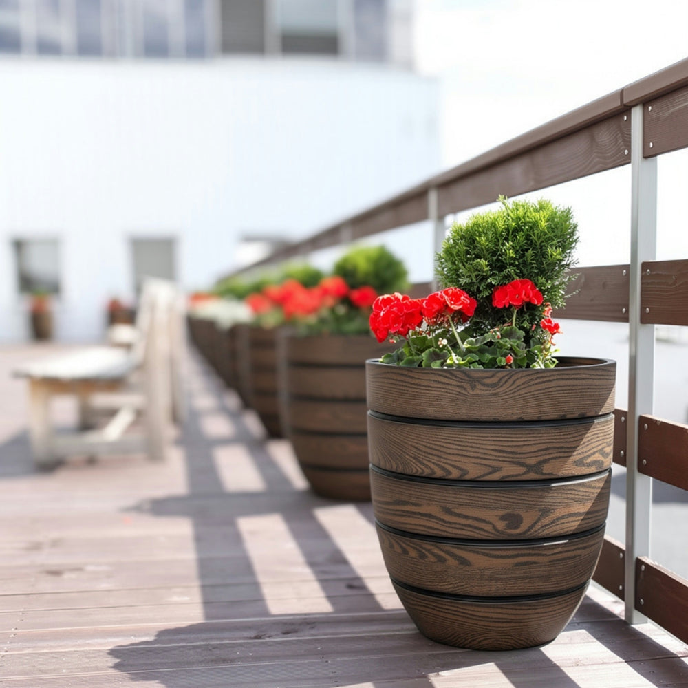 Aspen Round Wood Look Fiberglass Planter filled with red flowers on the patio.