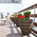 Aspen Round Wood Look Fiberglass Planter filled with red flowers on the patio.