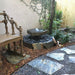 Basalt Bird Bath Fountain Kit on black peebels beside wooden chair