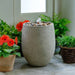 Bebel Pebble Fountain on concrete beside orange flowers