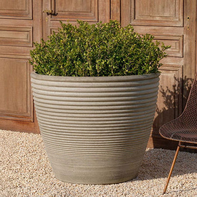 Bibendum Planter, Low Large on gravel filled with plants.
