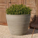 Bibendum Planter, Low Large on gravel filled with plants.