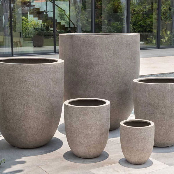 Bradford Planter in riverstone premium lite on concrete near swimming pool.
