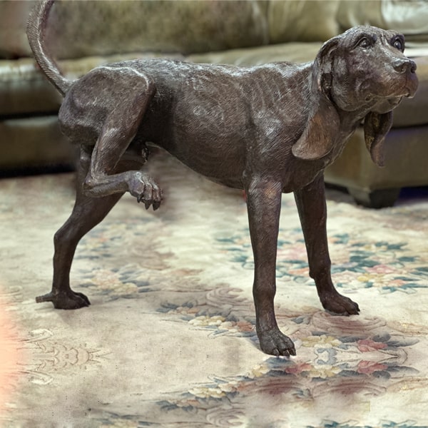 Bronze Peeing Dog Fountain Sculpture against green couch