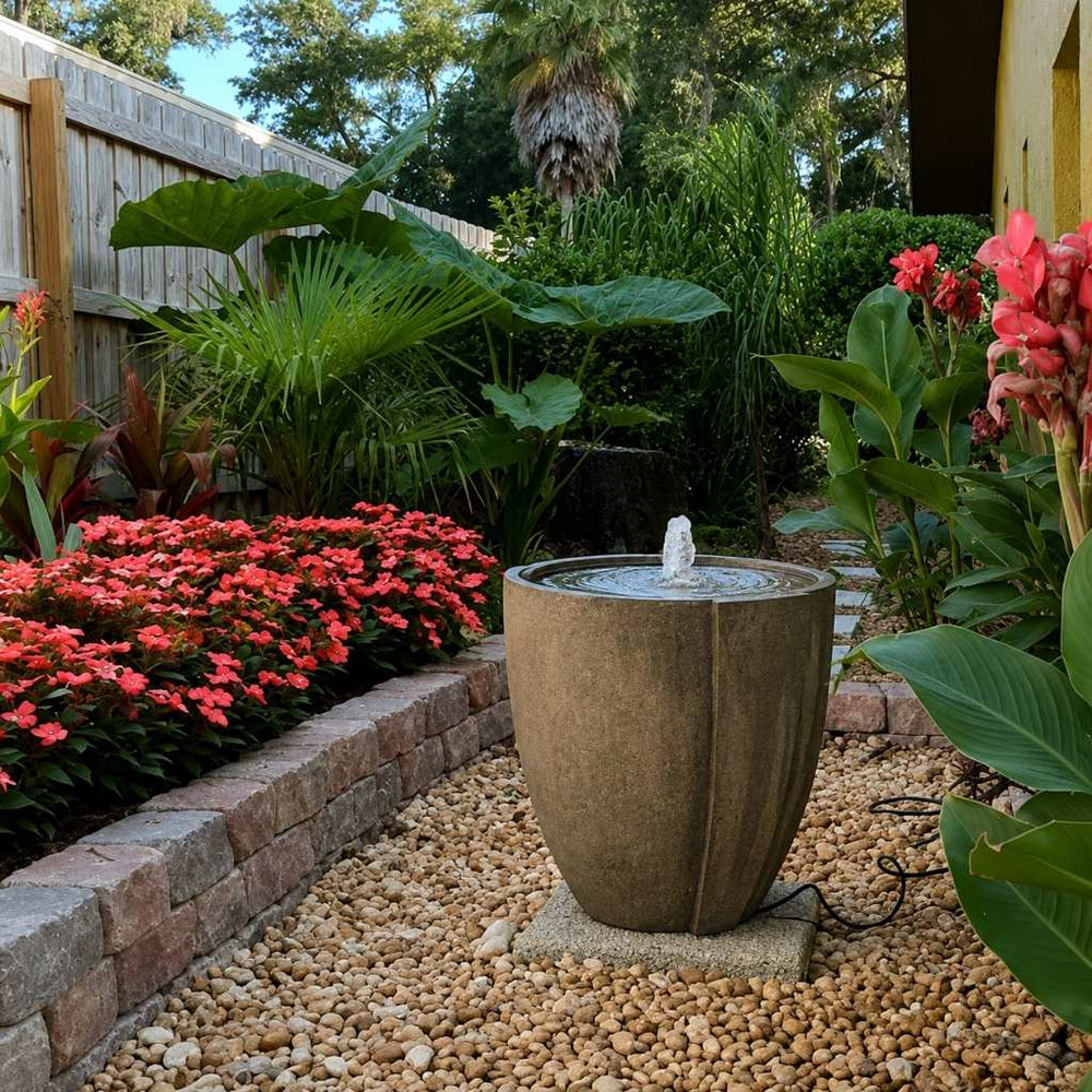 Concept Basin Fountain on gravel beside red flowers