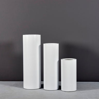 Corry Tall Cylinder Fiberglass Planter on concrete shown in different sizes.