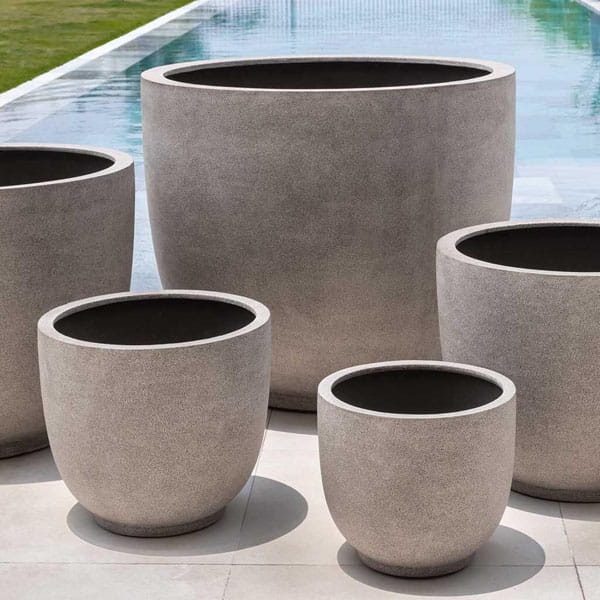 Danilo Planter, Extra Small in riverstone premium lite on concrete near a swimming pool.