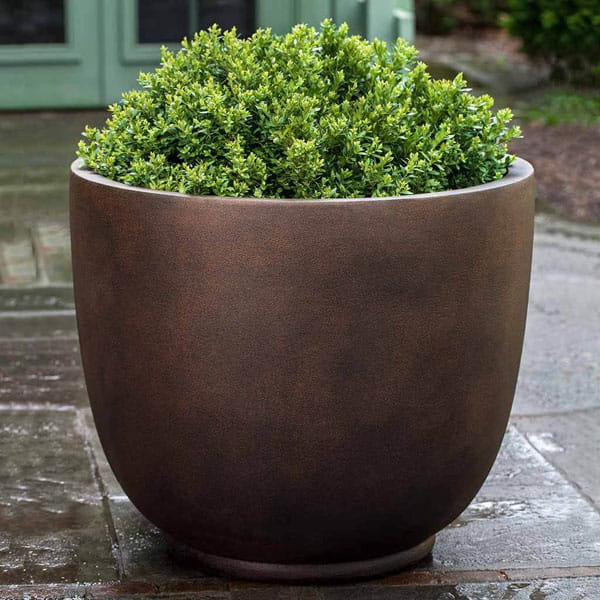 Danilo Planter, Medium in rust lite on concrete filled with plants.