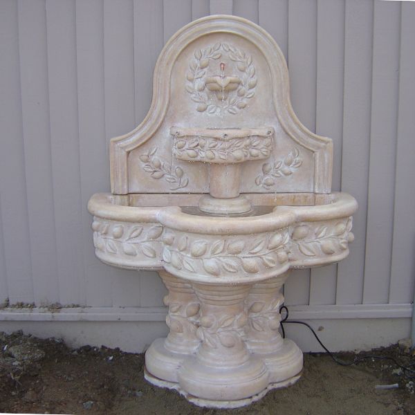 Deruta Lemon Wall Fountain in action against white fence.