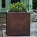Farnley Planter 3636 S/1 in rust lite on concrete filled with plants.