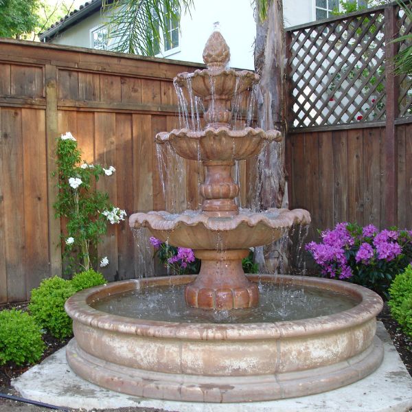 Garda Three Tier Pond Fountain on concrete near wooden fence.