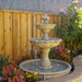 Gardenia Two Tier Pond Fountain against wooden fence in action.