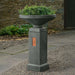 Gimlet Urn with Pedestal Copper on gravel filled with plants.