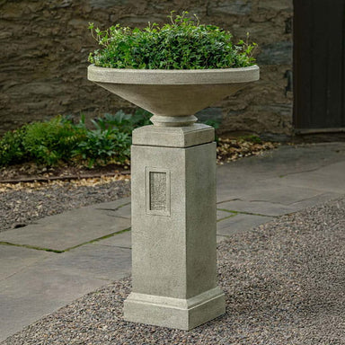 Gimlet Urn with Pedestal on gravel filled with plants.