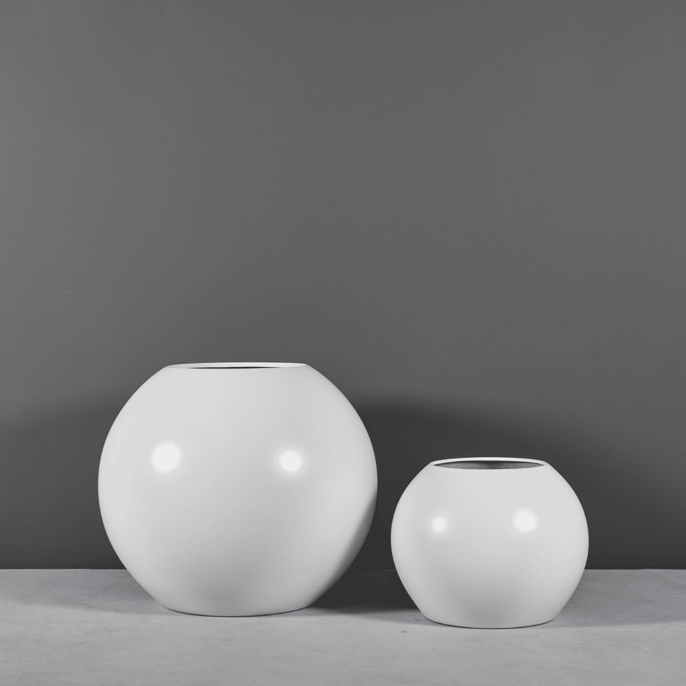 Globe Fiberglass Planter on concrete against gray background.
