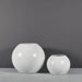 Globe Fiberglass Planter on concrete against gray background.