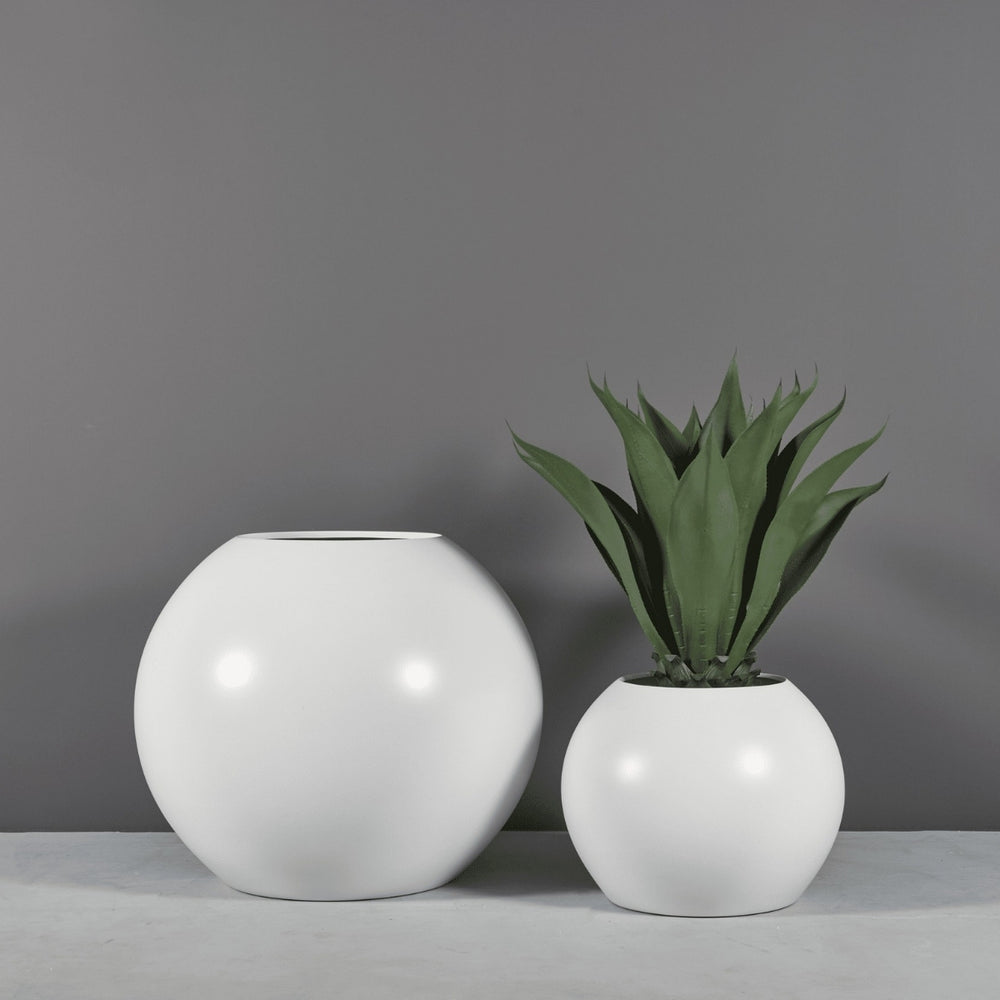 Globe Fiberglass Planter on concrete filled with plants shown with different sizes.