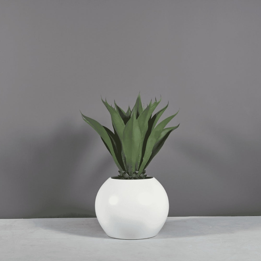 Globe Fiberglass Planter on concrete filled with plants.