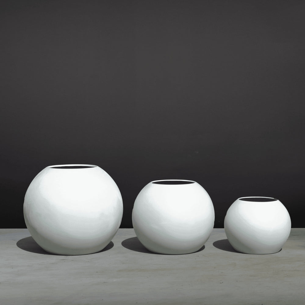 Globe Fiberglass Planter on concrete on concrete shown with different sizes.