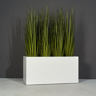Granada Wide Rectangle Fiberglass Planter on concrete filled with plants.