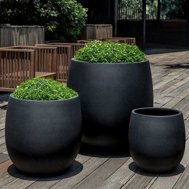 Guilford Planter, Medium in onyx black lite on concrete filled with plants.