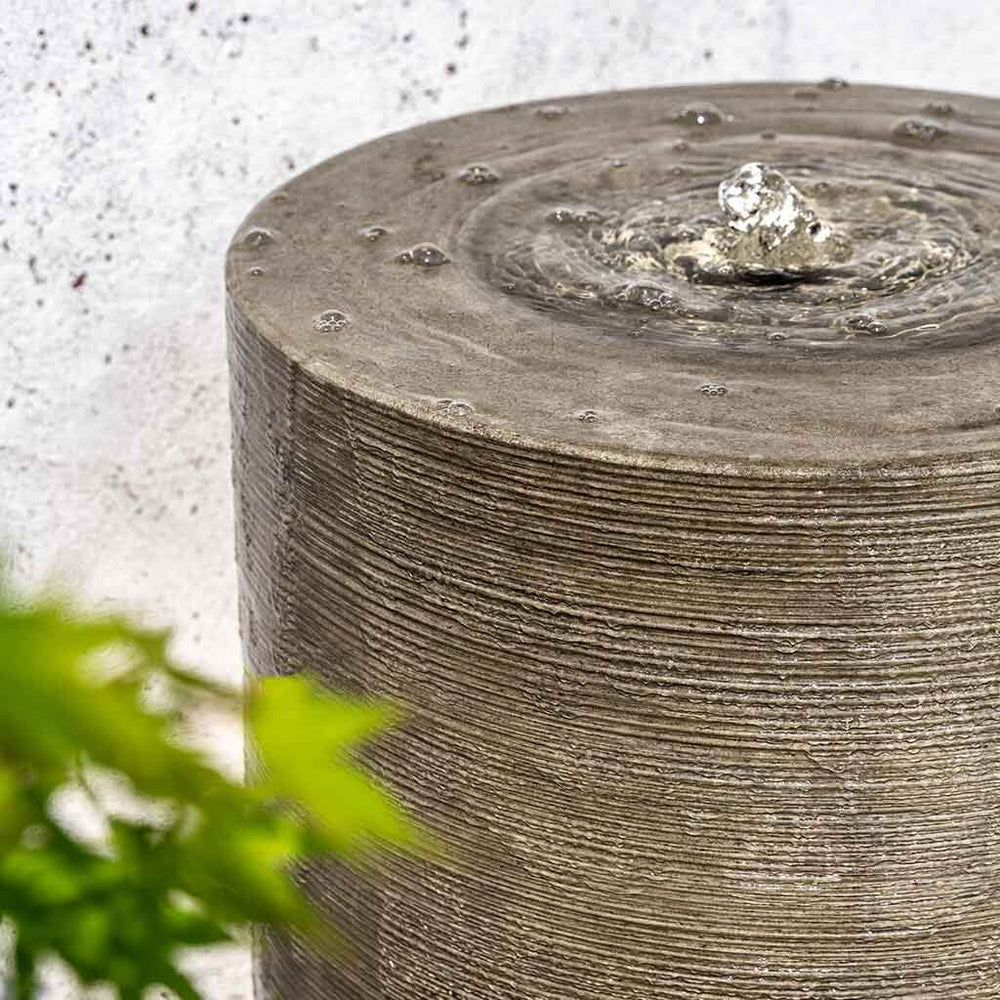 Large Cylinder Fountain on gravel in action upclose.