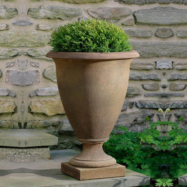 Lexington Urn Planter filled with plants in the backyard.