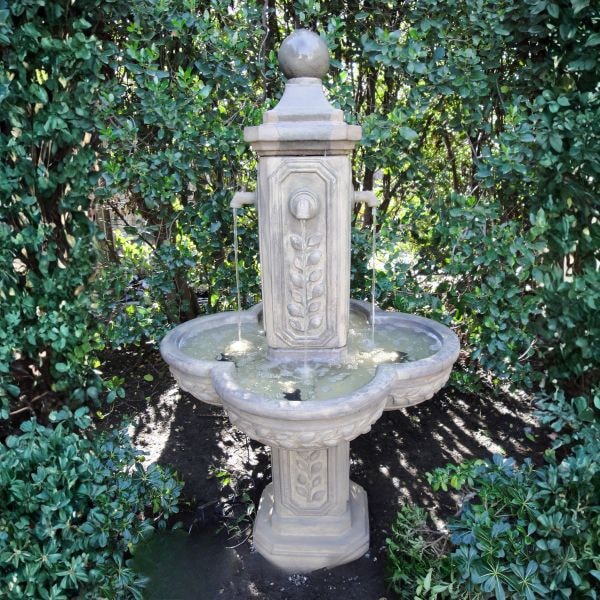 Limone Courtyard Fountain in action surrounded with green plants.