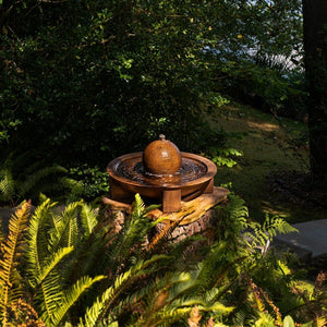 Low Zen Sphere fountain in action on tree stump surrounded by lush greenery