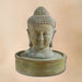 Meditation Buddha Fountain against brown background.