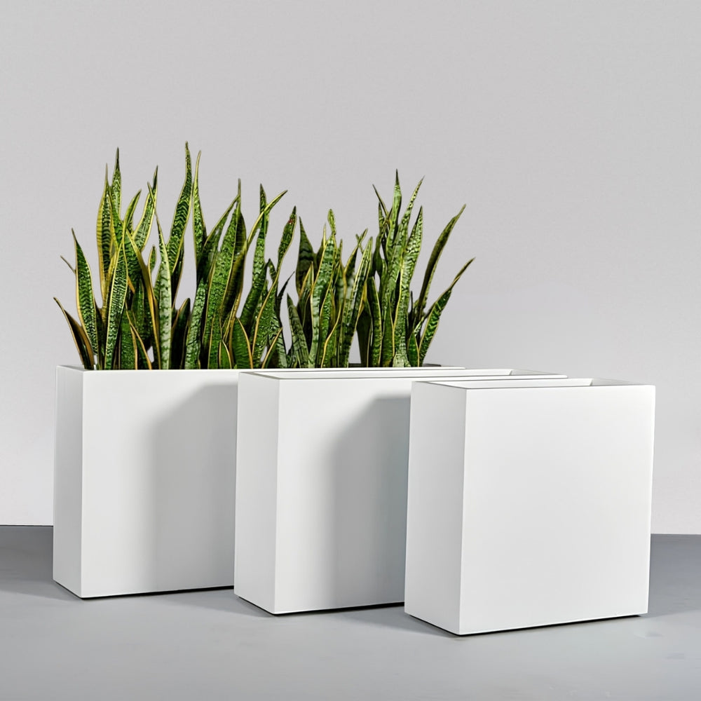 Milano Narrow Rectangle Planter against gray wall filled with plants. 