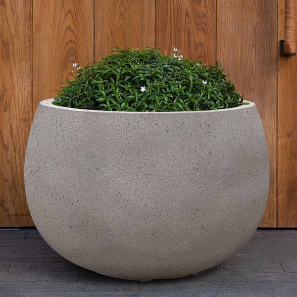Norfolk Planter Medium in stone grey lite on concrete filled with plants.