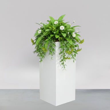 Perth Tall Corner Fiberglass Planter filled with plants against gray backdrop.