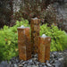 Polished Top Basalt Fountain Kit on black pebbles in the backyard