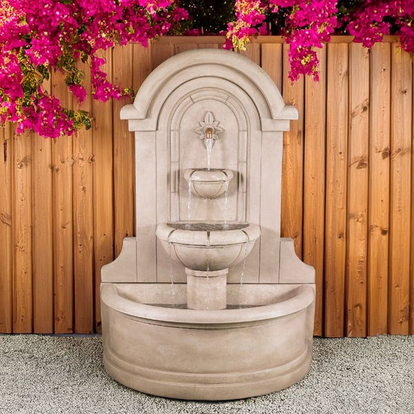 Riviera Wall Fountain on gravel against wooden-wall.