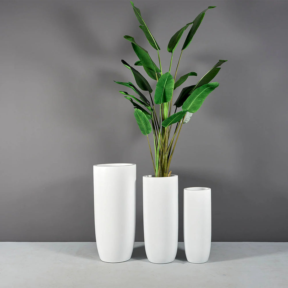 Saint Tropez Tall Bullet Round Fiberglass Planter shown with different sizes filled with plants.