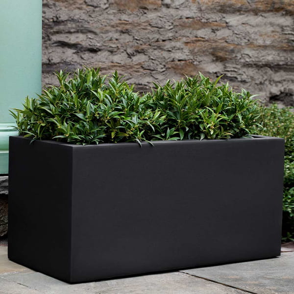 Sandal Planter 361818 S/1 in onyx black lite on concrete filled with plants.