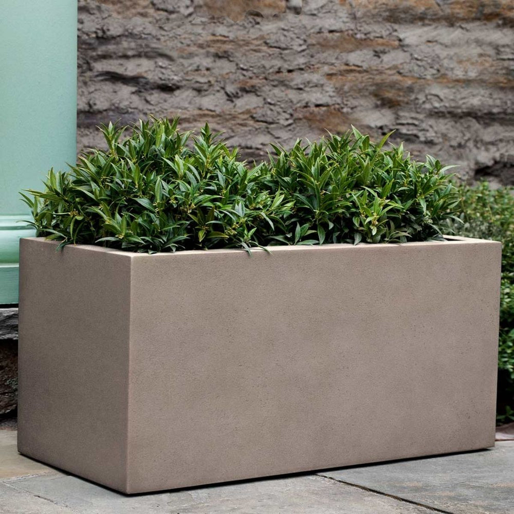 Sandal Planter 361818 S/1 in riverstone premium lite on concrete filled with plants.