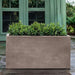 Sandal Planter 592424 S/1 in riverstone premium lite on concrete filled with plants.