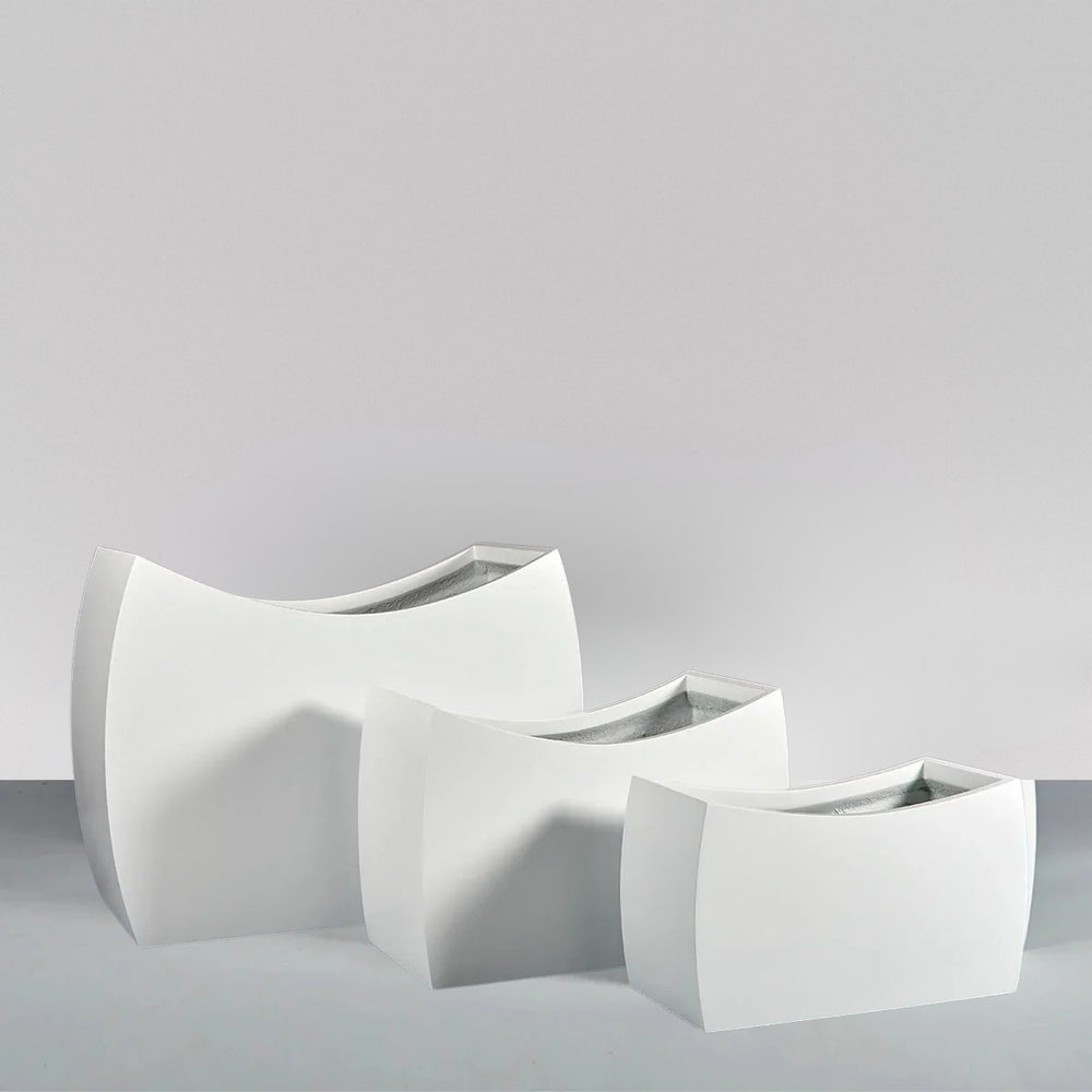 Seoul Modern Curved Rectangle Fiberglass Planter on concrete shown with three different sizes.